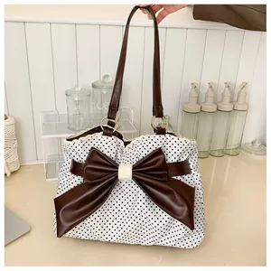Close-up of polka dot tote bag featuring a large brown leather bow with lace detail