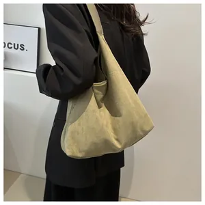 Detail of large olive suede crossbody bag showing soft texture and wide shoulder strap