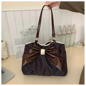 Detailed view of polka dot tote bag featuring leather bow and beige lace trim details