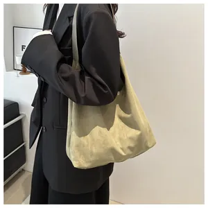 Detailed texture of olive green suede shoulder bag with high-capacity pockets and soft drape