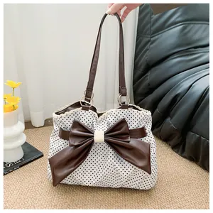 Polka dot canvas tote bag featuring a large leather bow and elegant lace trim detail