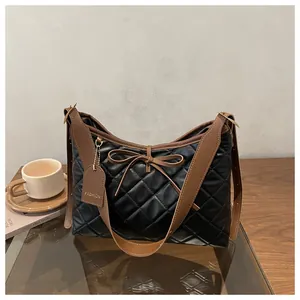Close-up of black quilted faux leather tote with brown strap and bow detail