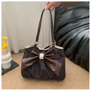 Close-up of black polka dot tote bag featuring a brown leather bow and white lace trim
