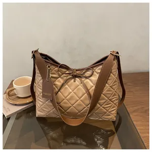 Close-up of khaki quilted tote bag featuring a leather bow and wide shoulder strap