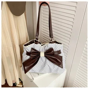 Polka dot tote bag detail showing oversized brown leather bow and lace edge trim