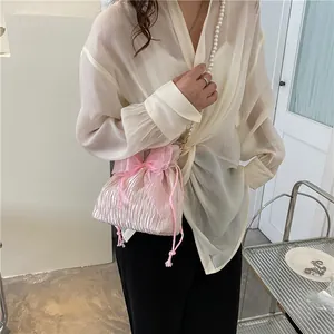 Pink pleated drawstring bucket bag with pearl chain strap and tulle bow accent
