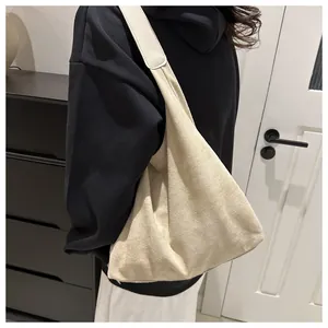 Minimalist beige suede hobo tote bag shown on model in a modern interior setting