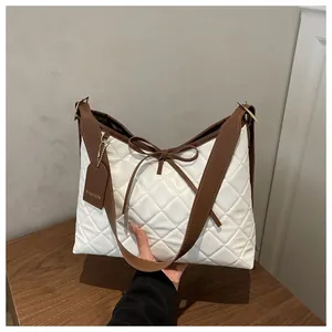 Detail of white quilted tote bag featuring a leather bow and a brown FASHION brand tag