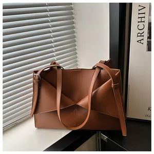 Détail du sac cabas en cuir marron au design géométrique plié moderne avec ses bandoulières