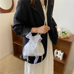 Detailed close-up of a white pleated bucket bag with pearl strap and organza bow