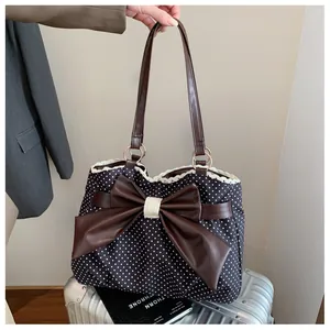 Close-up of polka dot tote bag with large brown bow detail and white lace trim