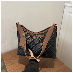 Detail of black quilted tote bag with brown bow accents and fashion brand tag