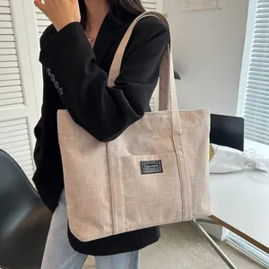 Close-up of minimalist cream canvas tote bag with fashion label and textured fabric detail