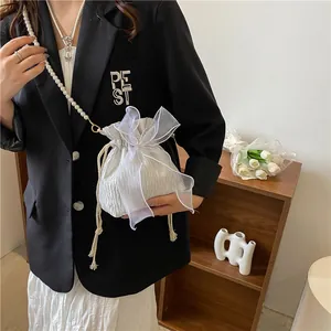 Detail of white pleated drawstring bucket bag with large organza bow and pearl strap