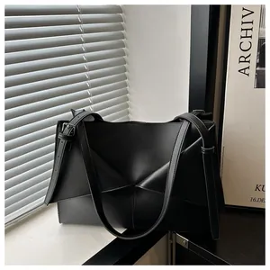 Détail du sac cabas en cuir mat noir avec pliage géométrique et boucles en métal argenté