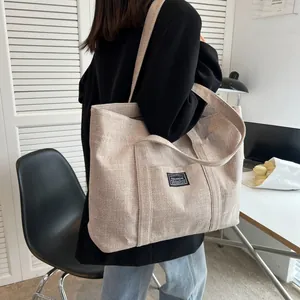 Close-up of beige canvas tote bag with black Fashion tag shown on female model