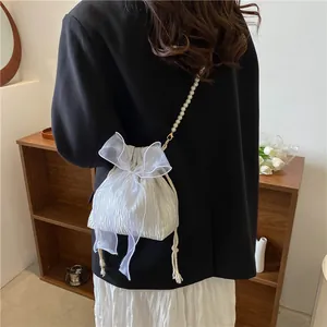 Detail of white pleated drawstring bucket bag with organza bow and pearl strap