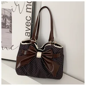 Detailed view of polka dot tote bag with large brown bow and delicate lace trim