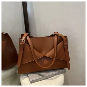 Détail du sac cabas en cuir caramel avec plis géométriques et boucles argentées fines