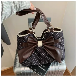 Close-up of polka dot tote bag with leather bow, lace trim and metallic ring detail