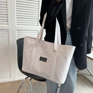 Detail of canvas tote bag with woven straps and black fashion label on the front