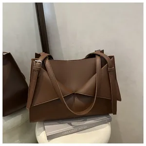 Détail d'un sac cabas marron en similicuir avec plis géométriques et boucle métallique