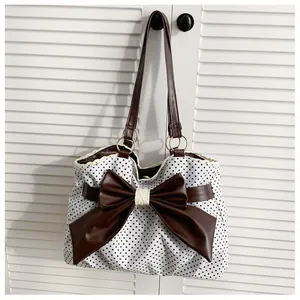 Close-up of white polka dot canvas tote with large brown leather bow and lace trim