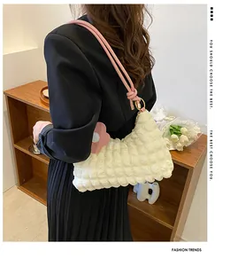 Détail du sac blanc à texture gaufrée avec pendentif floral rose et sangle rose