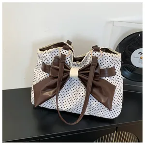 Close-up of retro polka dot tote bag with large brown bow and delicate lace trim