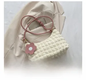 Détail du tissu gaufré pop-corn et de la bandoulière nouée rose sur un sac à main