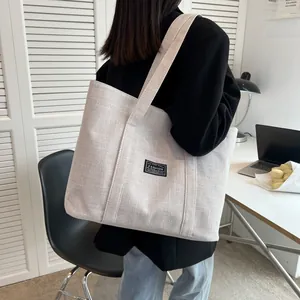 Detail of canvas tote bag showing durable fabric texture and fashion label on shoulder bag