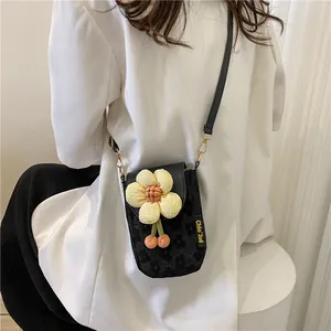 Detail of black fabric phone bag with yellow floral ornament and gold metal hook