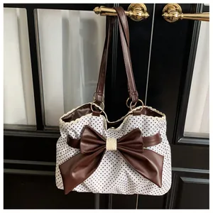 Close-up of polka dot tote bag with large brown bow and lace trim hanging on door