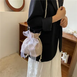 Pink pleated bucket bag with oversized organza bow and white pearl strap on model