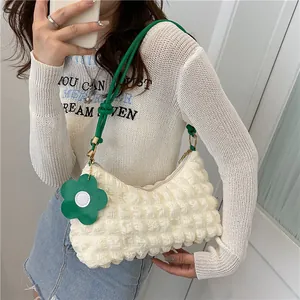 Détail du sac à bandoulière crème texturé avec sangle verte nouée et breloque fleurie
