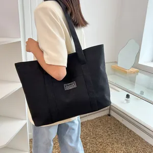 Side view of a large black canvas tote bag worn by a model for daily use