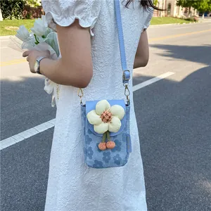 Détail du petit sac bandoulière bleu clair avec fleur 3D et pompons roses décoratifs