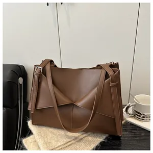 Détail du sac cabas en cuir marron foncé avec pli géométrique et boucle en argent poli