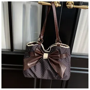 Detail of vintage polka dot tote bag featuring a large leather bow and delicate lace trim