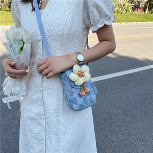 Détail d'un sac bandoulière bleu à fleurs avec fleur 3D porté sur une robe blanche