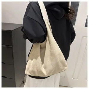Minimalist large beige suede shoulder bag with wide strap in a clean lifestyle setting