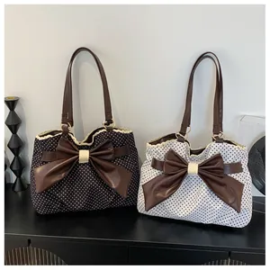 Close-up of polka dot tote bags featuring large brown leather bows and lace trim detail