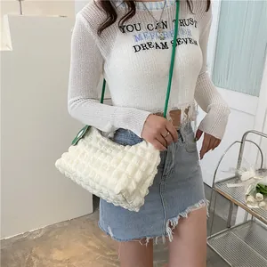 Détail du sac à bandoulière blanc en seersucker avec sangle verte et motif à pois latéral