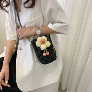 Détail du sac bandoulière tissé noir avec fleur de soleil jaune et pendentifs cerises