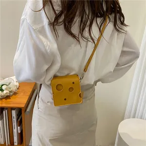 Mini sac à bandoulière en forme de fromage jaune porté par un mannequin stylé