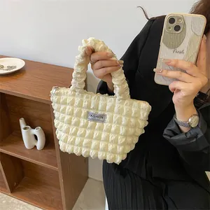 Detail of cream bubble textured tote bag with Fashion Instinct label and zipper closure