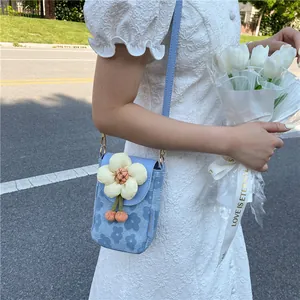 Detail view of light blue floral phone bag with a large white 3D flower and cherry charm