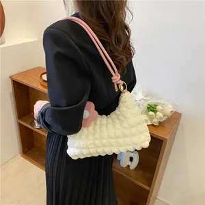Détail du sac bandoulière blanc cassé matelassé avec bandoulière rose et charm tournesol