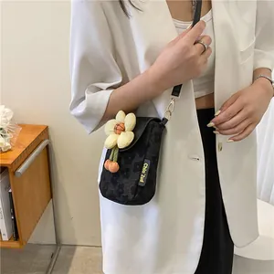 Détail du motif marguerite noir et du pendentif fleur 3D sur le petit sac bandoulière