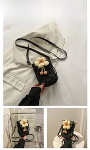 Detail of black mini crossbody bag with yellow plush flower and Chlo 2ud side label